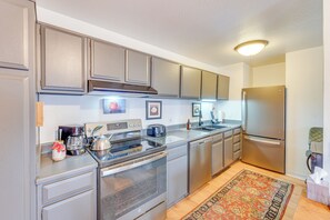 A modern kitchen with stainless steel appliances, wooden cabinets, and a patterned rug.