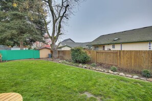 A backyard with a wooden fence, a tree, and a well-maintained lawn. - Eugene Vacation Home: 8 Mi to University of Oregon (Eugene)