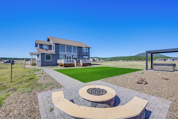 A residential property with a two-story house, a landscaped lawn, and a circular outdoor seating area.