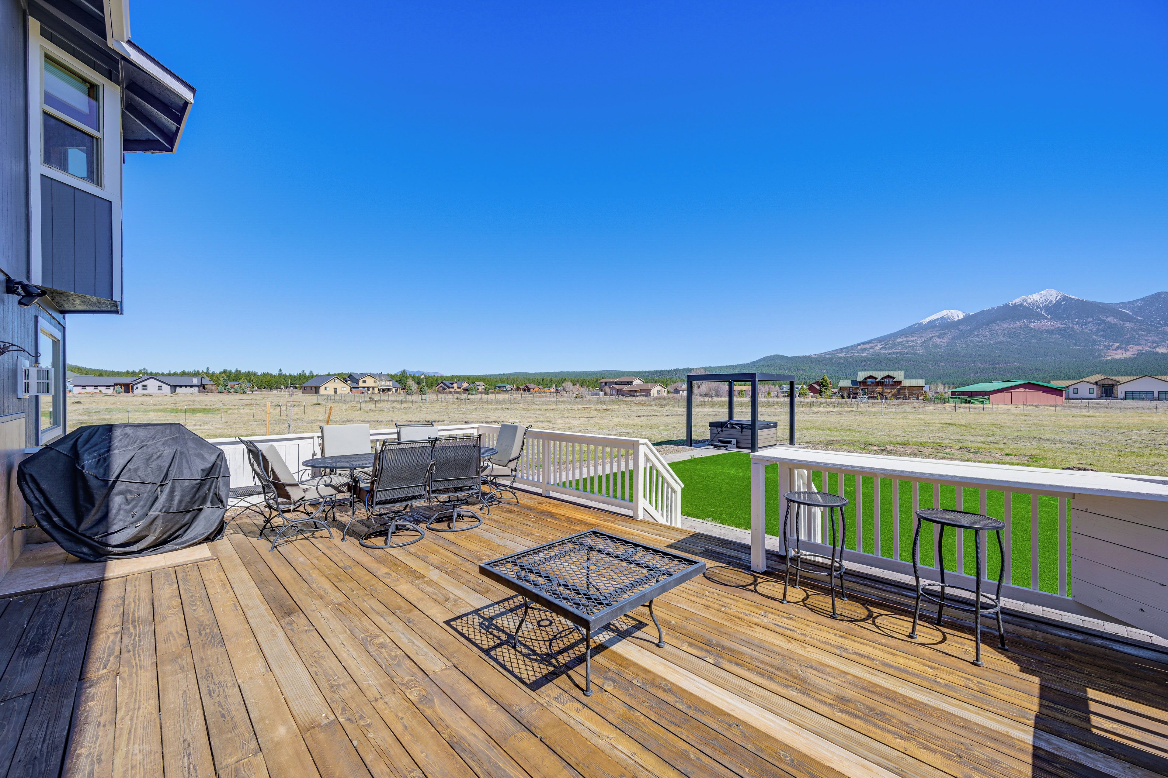Une terrasse en bois avec des meubles d’extérieur, un barbecue abrité et une vue sur une montagne.