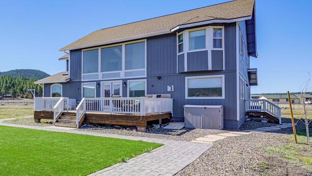 Une maison à deux étages dotée d’une terrasse, de grandes fenêtres et d’un garage.