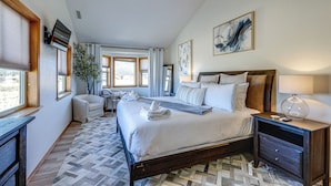 Une chambre d’hôtel avec un grand lit, un bureau, une chaise, une télévision et une fenêtre avec des rideaux.