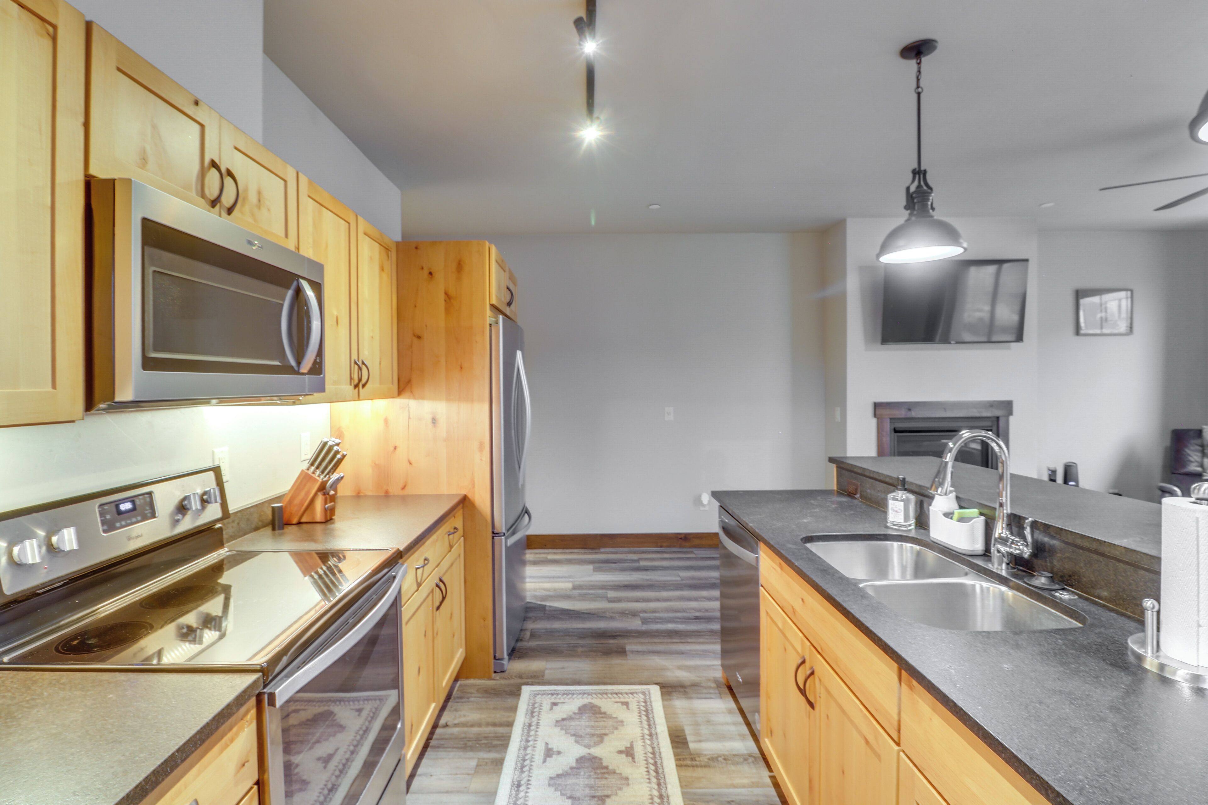 A modern kitchen with wooden cabinets, stainless steel appliances, and a large island with a sink.