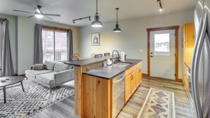 A modern kitchen with a central island, built-in appliances, and a dining area with a sofa and coffee table. - Downtown Columbia Falls Condo: 16 Mi to Ski Resort (Columbia Falls)