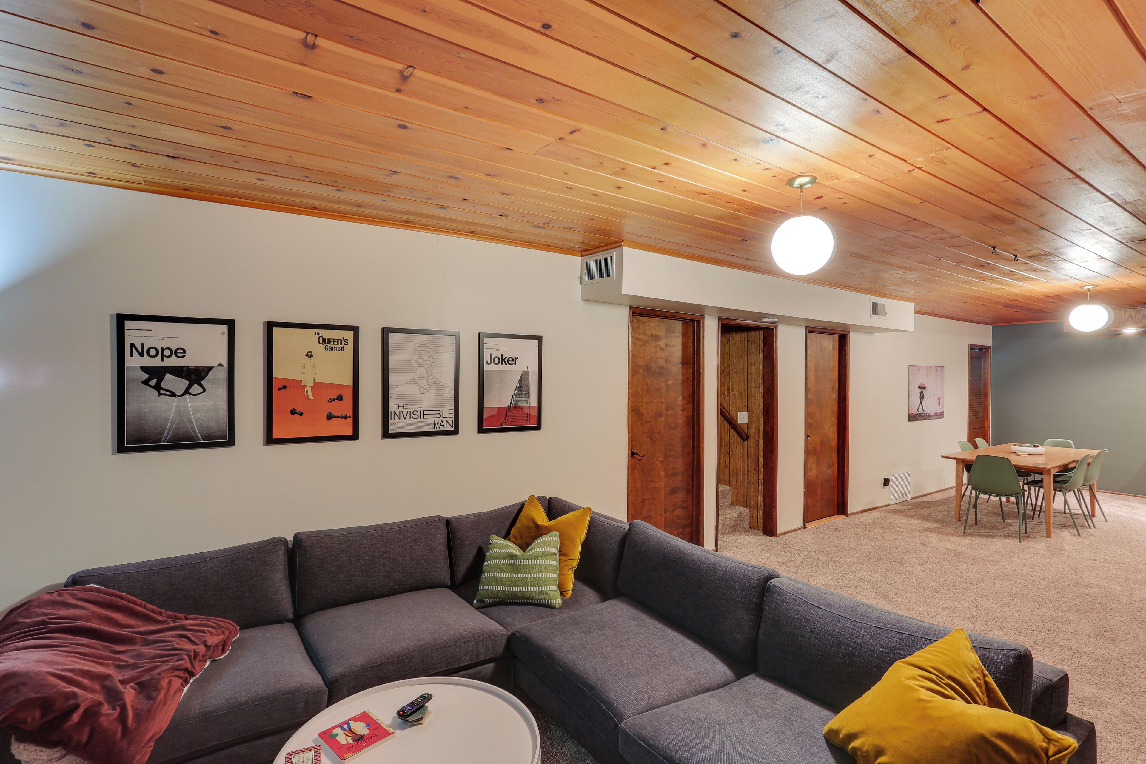A modern living room with a grey sectional sofa, a round coffee table, and a dining area with a wooden table and chairs.