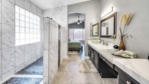 A modern bathroom with a walk-in shower, a large mirror, and a vanity with a sink. - Gold Canyon Superstition Foothills Retreat w/ Pool (Gold Canyon)