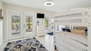 Un dormitorio con literas, un televisor en la pared y vistas al exterior desde la puerta.