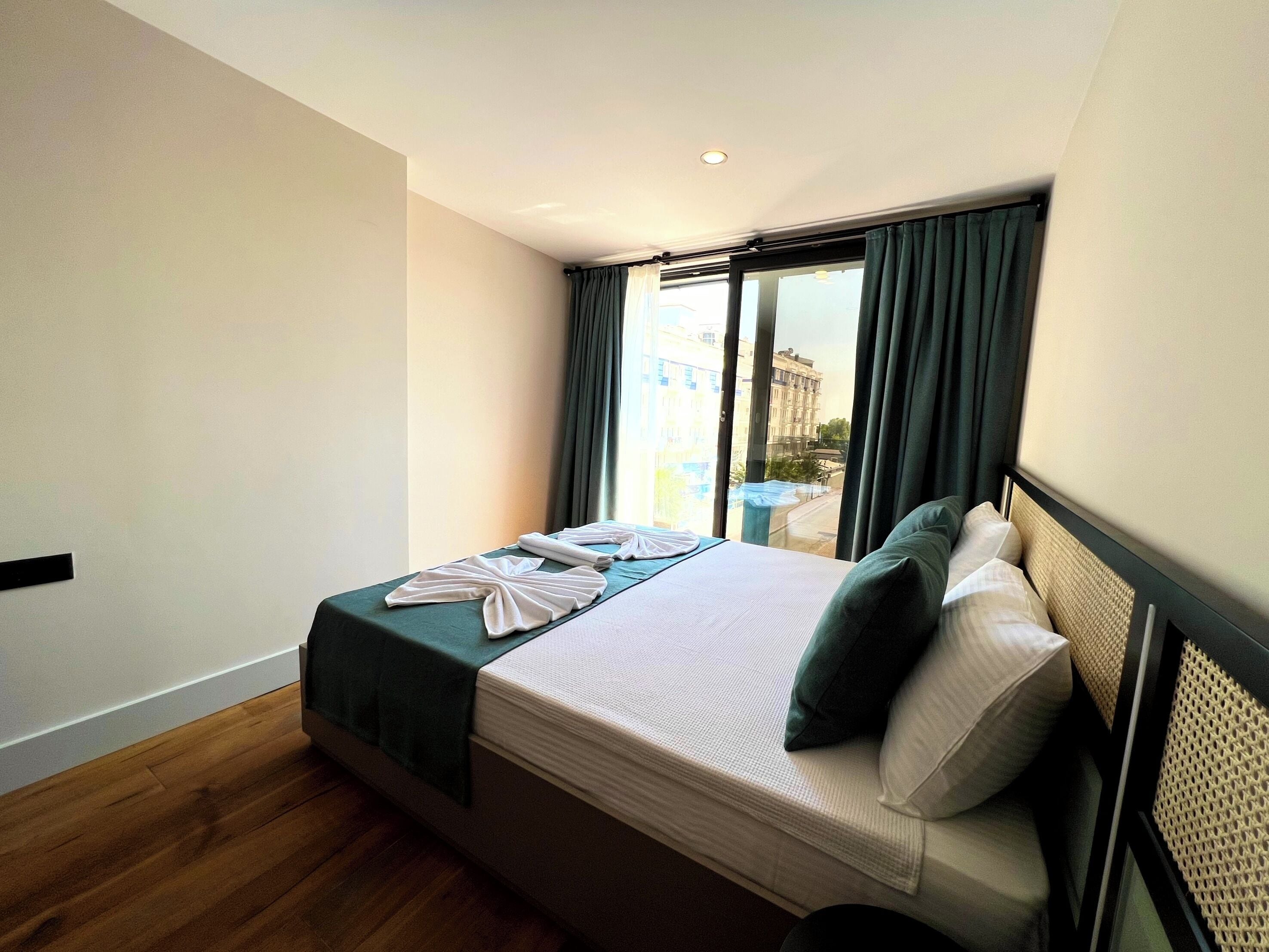 Una habitación de hotel con una cama, vistas de la ciudad a través de una ventana y una mesita junto a la ventana.
