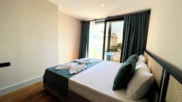 A hotel room with a bed, a view of the city through a window, and a small table by the window.