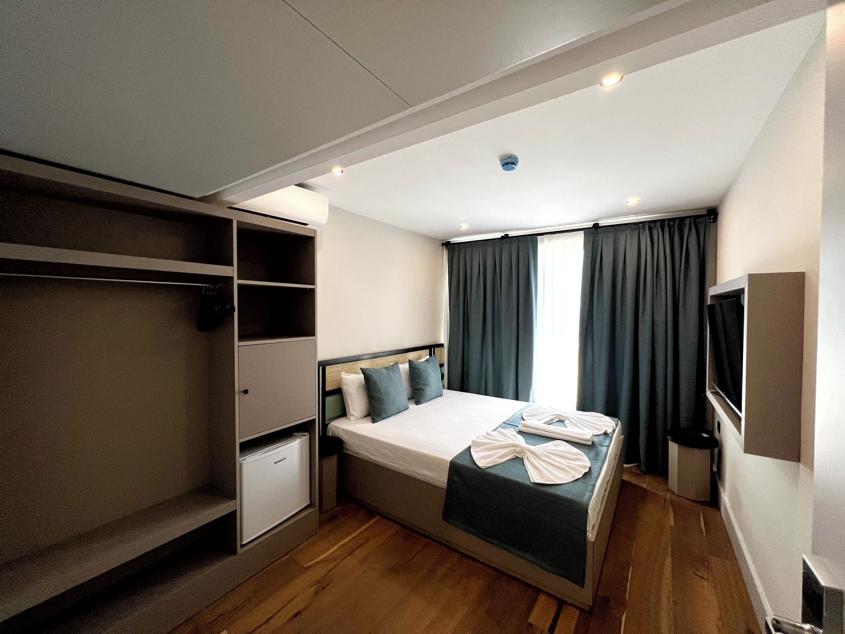 Ein Hotelzimmer mit Bett, Schrank, kleinem Schreibtisch und Fernseher.