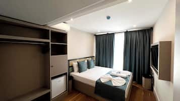 Ein Hotelzimmer mit Bett, Schrank, kleinem Schreibtisch und Fernseher.