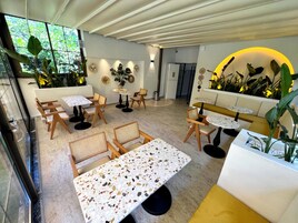Un interior moderno con comedor que incluye sillas y mesas de madera con acabado de terrazo.