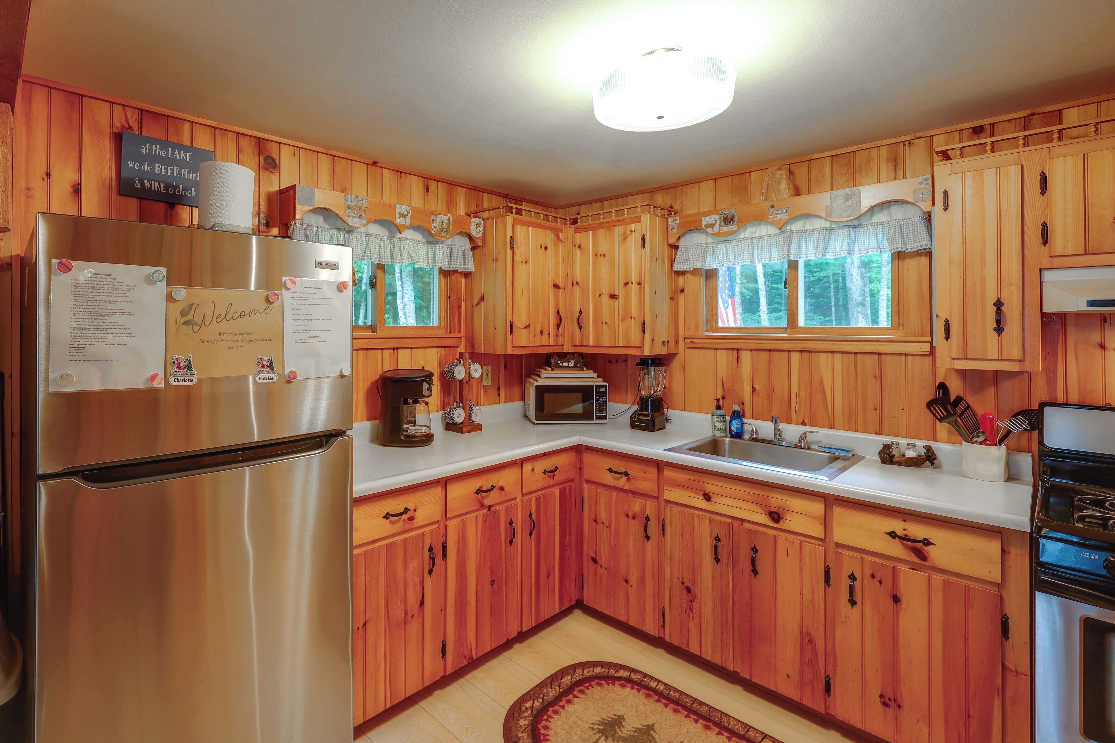 A wooden kitchen with a refrigerator, microwave, stove, and sink.
