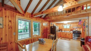 L’intérieur d’un chalet en bois comprend un coin repas, une cuisine et un canapé en cuir rouge.
