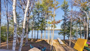 Un chalet au bord du lac, doté d’une terrasse, de meubles d’extérieur et offrant une vue sur le lac.