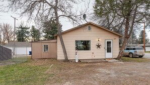 A small, single-story building with a door and windows, surrounded by trees and a fence. - Choteau Vacation Rental w/ Yard: Walk to Downtown! (Choteau)