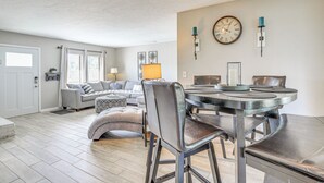 Un coin repas avec une table ronde, des chaises et une horloge au mur.