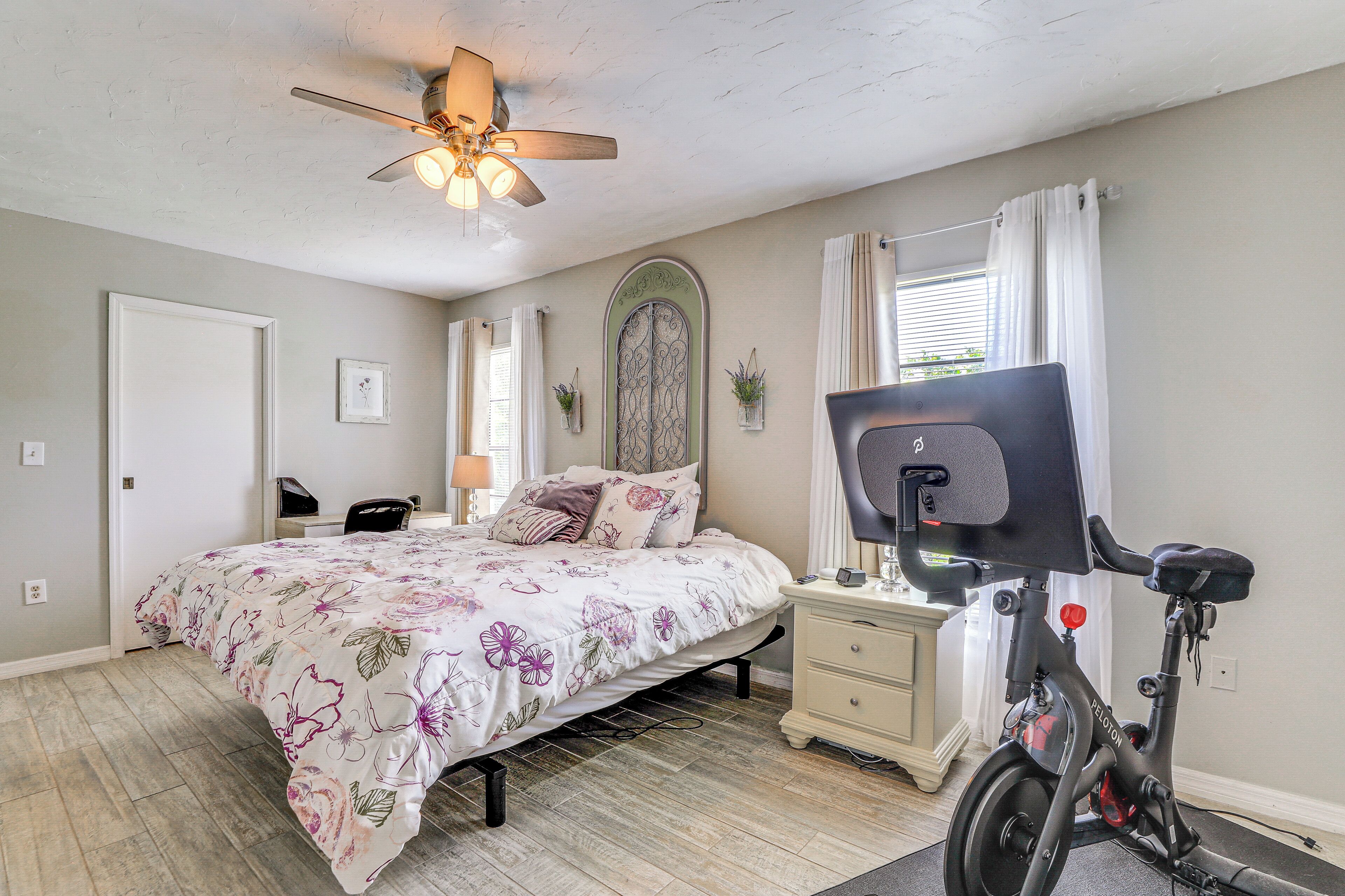 Un dormitorio con cama, escritorio, bicicleta y ventilador de techo.