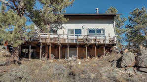 A two-story house with a wooden deck and a large wheel. - Red Feather Lakes Cabin w/ Deck & Views! (Red Feather Lakes)