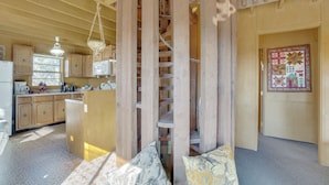 A rustic cabin interior with a wooden staircase, a kitchen area with wooden cabinets, and a patterned rug. - Red Feather Lakes Cabin w/ Deck & Views! (Red Feather Lakes)