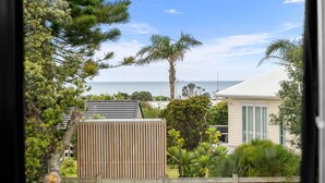 Una propiedad costera con valla de madera, una casa con techo inclinado y vista al mar.