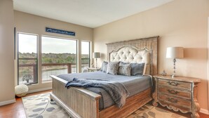 A bedroom with a large bed, a nightstand, and a view of the outdoors. - Lakefront Townhome in Pottsboro: Pets Welcome! (Pottsboro)