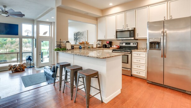 A modern kitchen with a large island, stainless steel appliances, and a view to the outside. - Lakefront Townhome in Pottsboro: Pets Welcome! (Pottsboro)