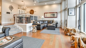 A spacious living room with a leather sofa, a coffee table, and a dining area with a chandelier. - Lakefront Townhome in Pottsboro: Pets Welcome! (Pottsboro)