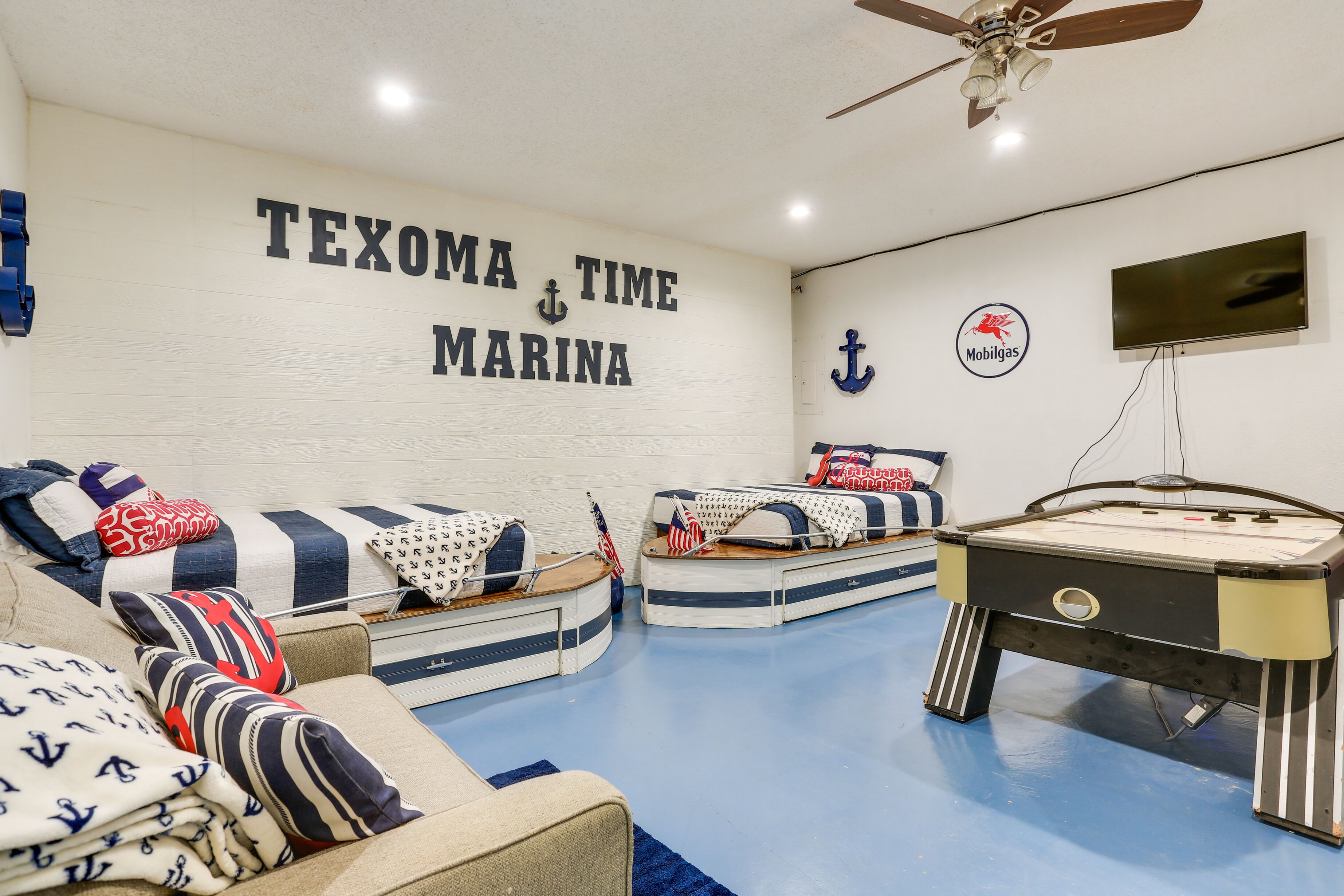 A nautical-themed room with a sofa, two bunk beds, and a pool table.