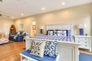A bedroom with a large bed, a nightstand, a dresser, a sofa, and a chair.