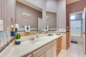 A bathroom with striped wallpaper, a large mirror, a white sink, and a door leading to another room. - Pottsboro Townhome w/ Deck, Lake Access & More! (Pottsboro)