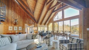 A spacious living area with a wooden ceiling, large windows, and a mounted deer head. - Mountain-view Cashiers Home: Near High Hampton!- (Cashiers)