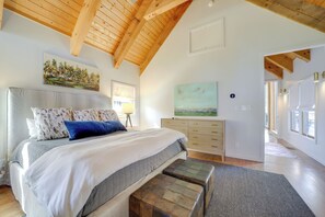 A spacious bedroom with a large bed, wooden ceiling beams, and a view of the outdoors. - Mountain-view Cashiers Home: Near High Hampton!- (Cashiers)