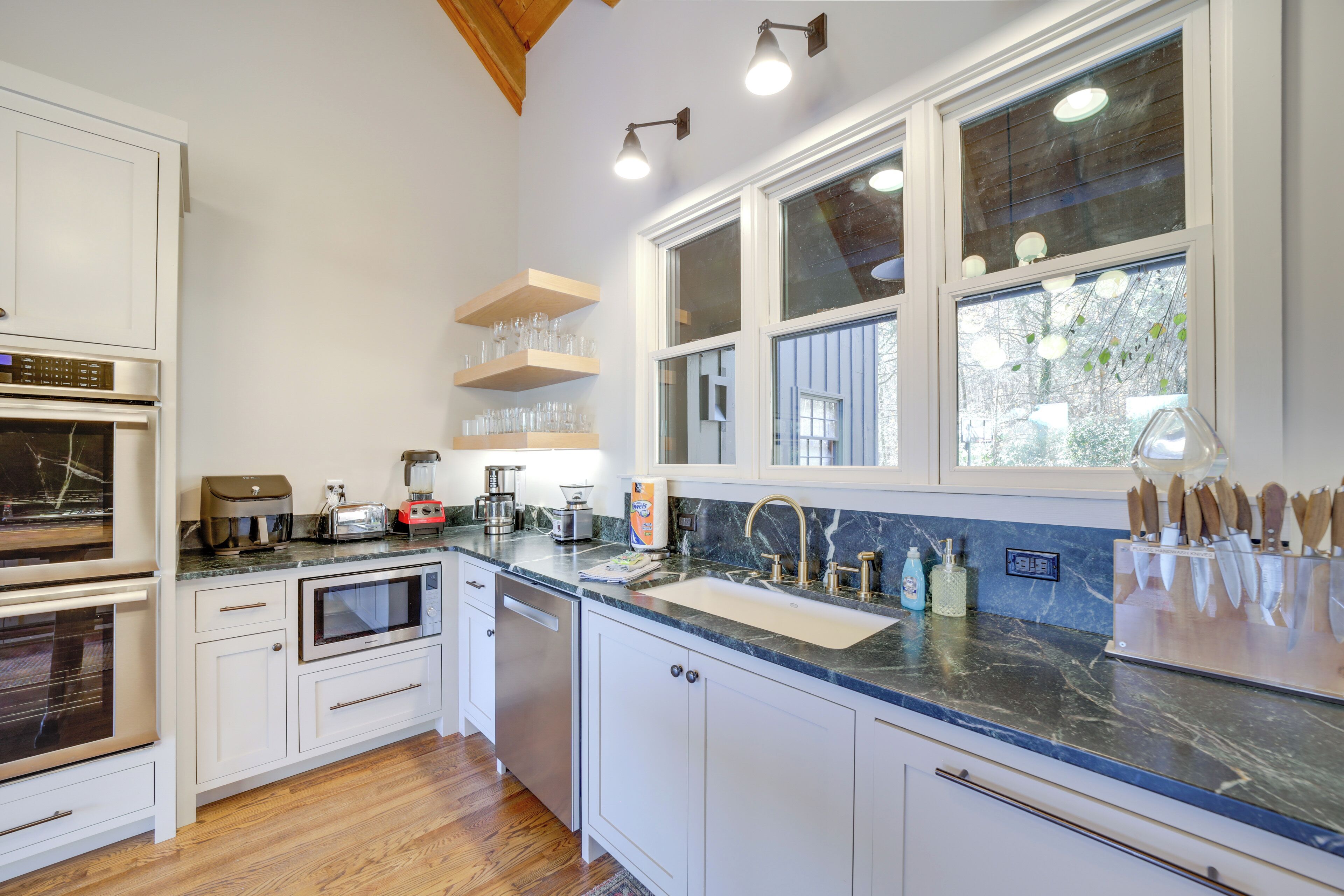A modern kitchen with white cabinetry, a marble countertop, and a built-in oven.