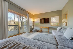 A bedroom with a large sliding glass door leading to a balcony, a sofa, a small table, and a lamp. - Mountain-view Cashiers Home: Near High Hampton!- (Cashiers)