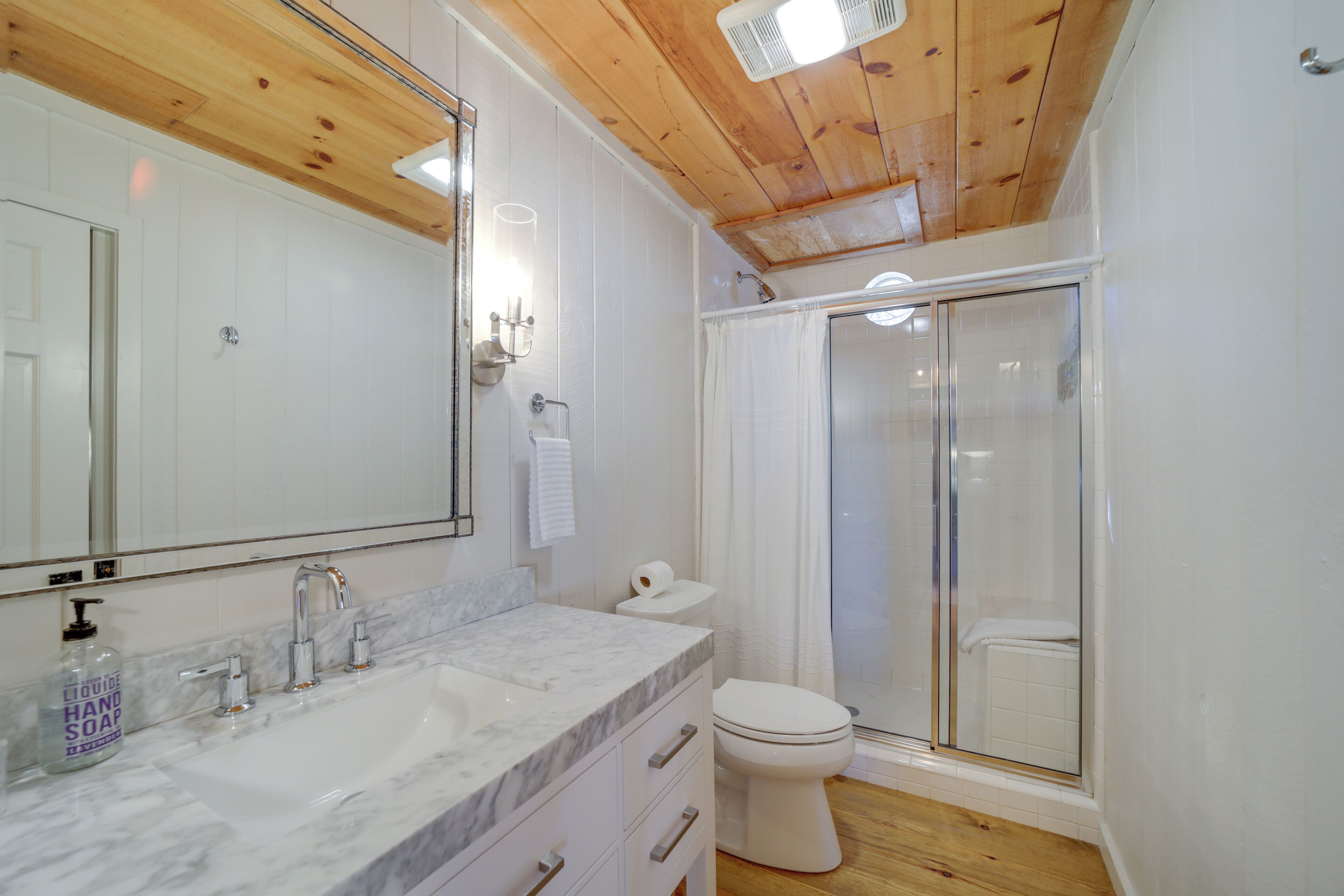 Une salle de bain avec un lavabo en marbre, des toilettes et une cabine de douche en verre.