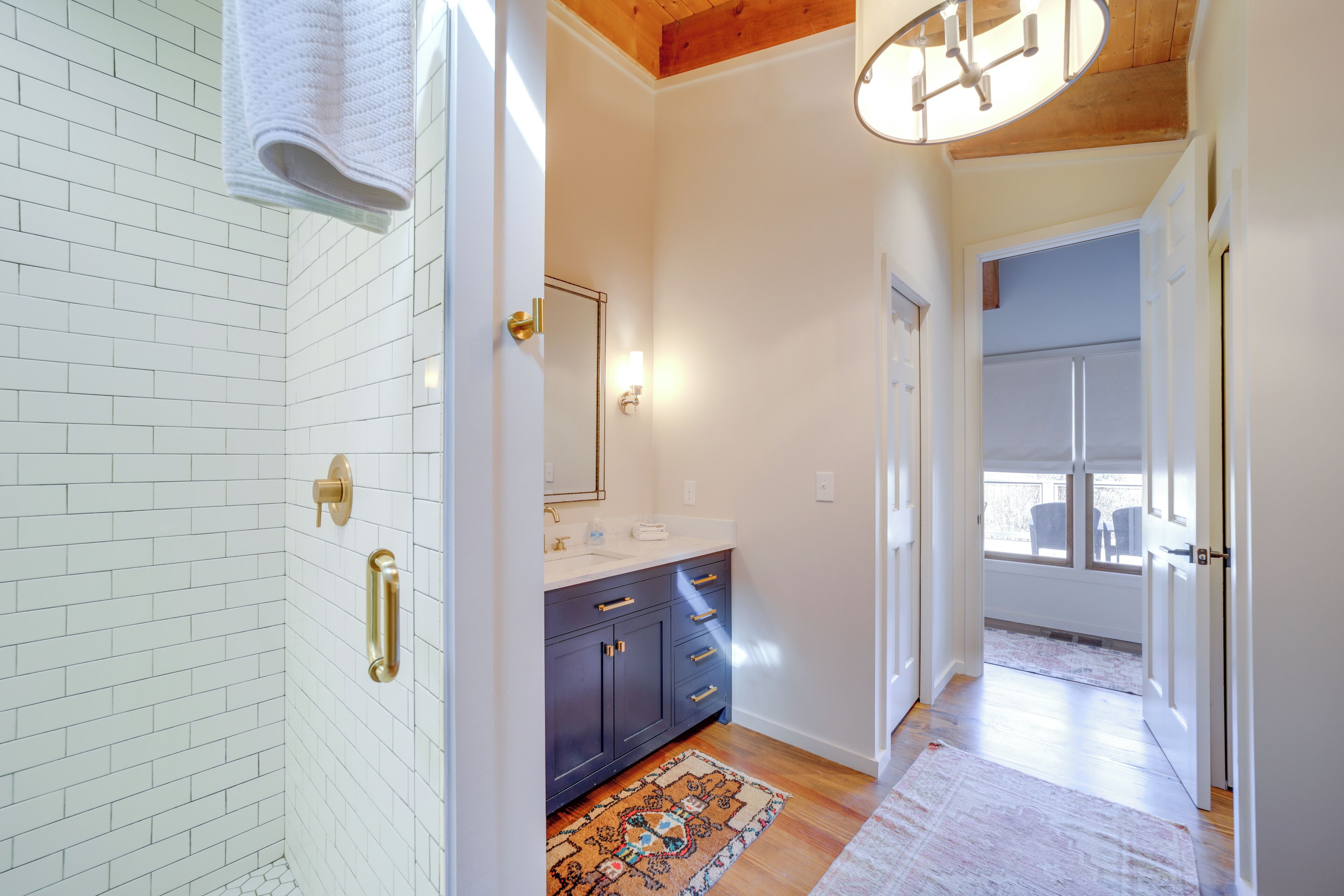 A modern bathroom with white subway tiles, a dark vanity, a mirror, and a light fixture.