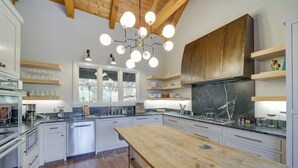 A modern kitchen with white cabinets, a wooden dining table, and a central island. - Mountain-view Cashiers Home: Near High Hampton!- (Cashiers)