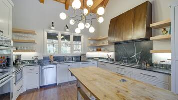 A modern kitchen with white cabinets, a wooden dining table, and a central island.