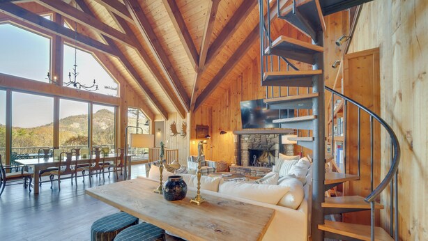 A spacious wooden interior with a dining area, a fireplace, and a spiral staircase. - Mountain-view Cashiers Home: Near High Hampton!- (Cashiers)