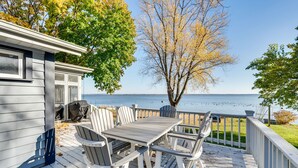A wooden deck with a table and chairs, overlooking a body of water. - Lakefront Edgerton Cottage w/ Deck & Grill! (Edgerton)