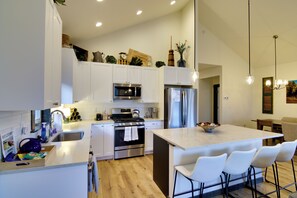 A modern kitchen with white cabinets, stainless steel appliances, and a central island with bar seating. - Pet-friendly Bozeman Home ~ 7 Mi to Downtown! (Bozeman)
