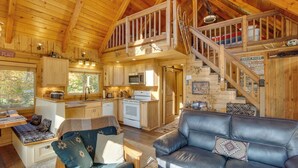 Interior acogedor de una cabaña con cocina, comedor y sala de estar con un sofá de cuero.