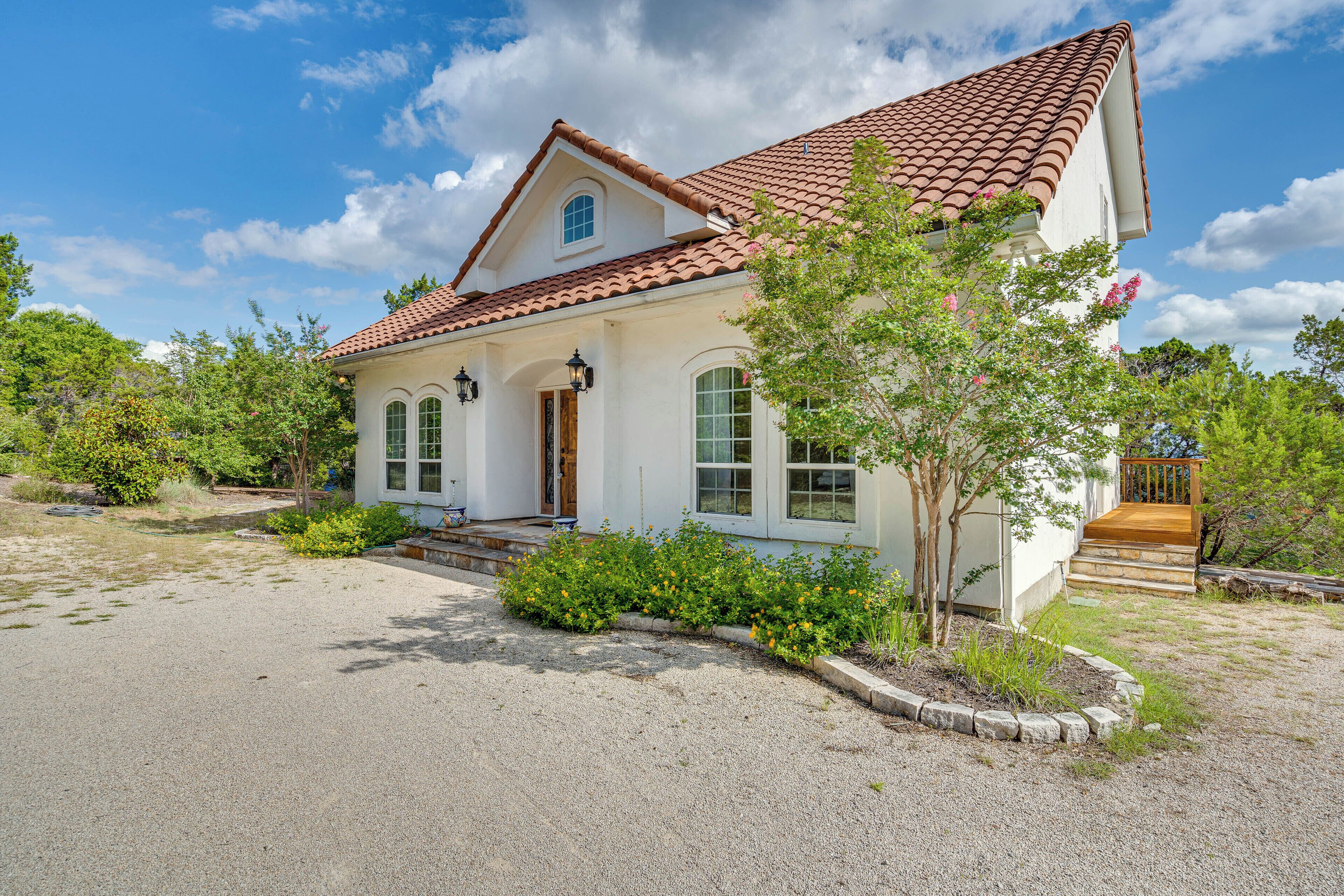 A two-story house with a red-tiled roof, a front porch, and a small garden area.