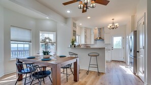 A modern kitchen with wooden flooring, white cabinets, a central island, and bar stools. - Jonestown Retreat w/ Deck: 6 Mi to Lake Travis! (Leander)