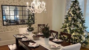 A dining room with a chandelier, a Christmas tree, and a mirror on the wall. - Historic district- yard, putting green, firepit (Saint Augustine)