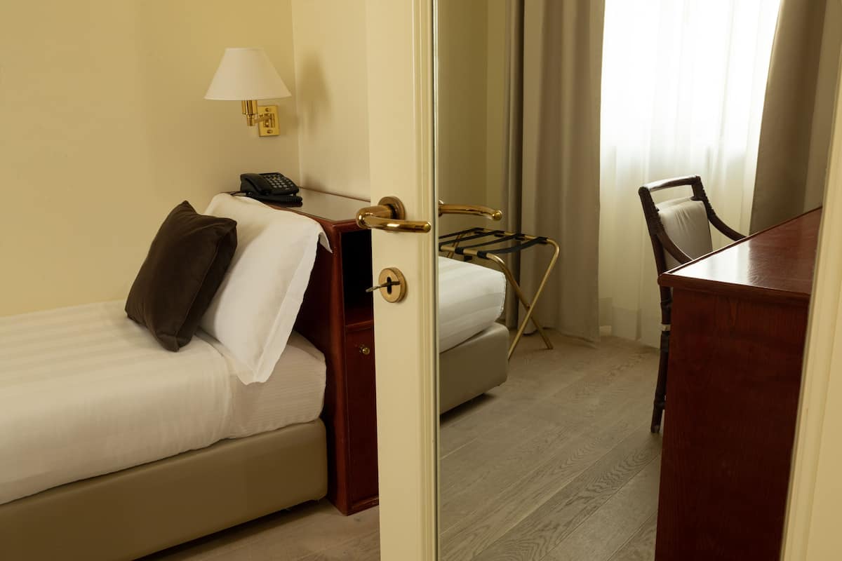 Una habitación de hotel con una cama, un escritorio, una silla, una lámpara y un teléfono.
