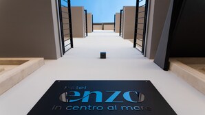 A hallway leading to a black sign with "hotel ENZO in centro al mare" written on it. - Hotel Enzo (Porto Recanati)