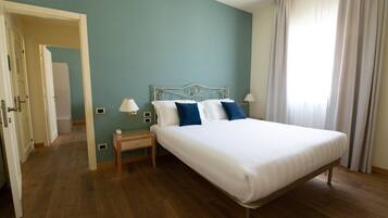 A bedroom with a single bed, a bedside table, a lamp, and a window with curtains.