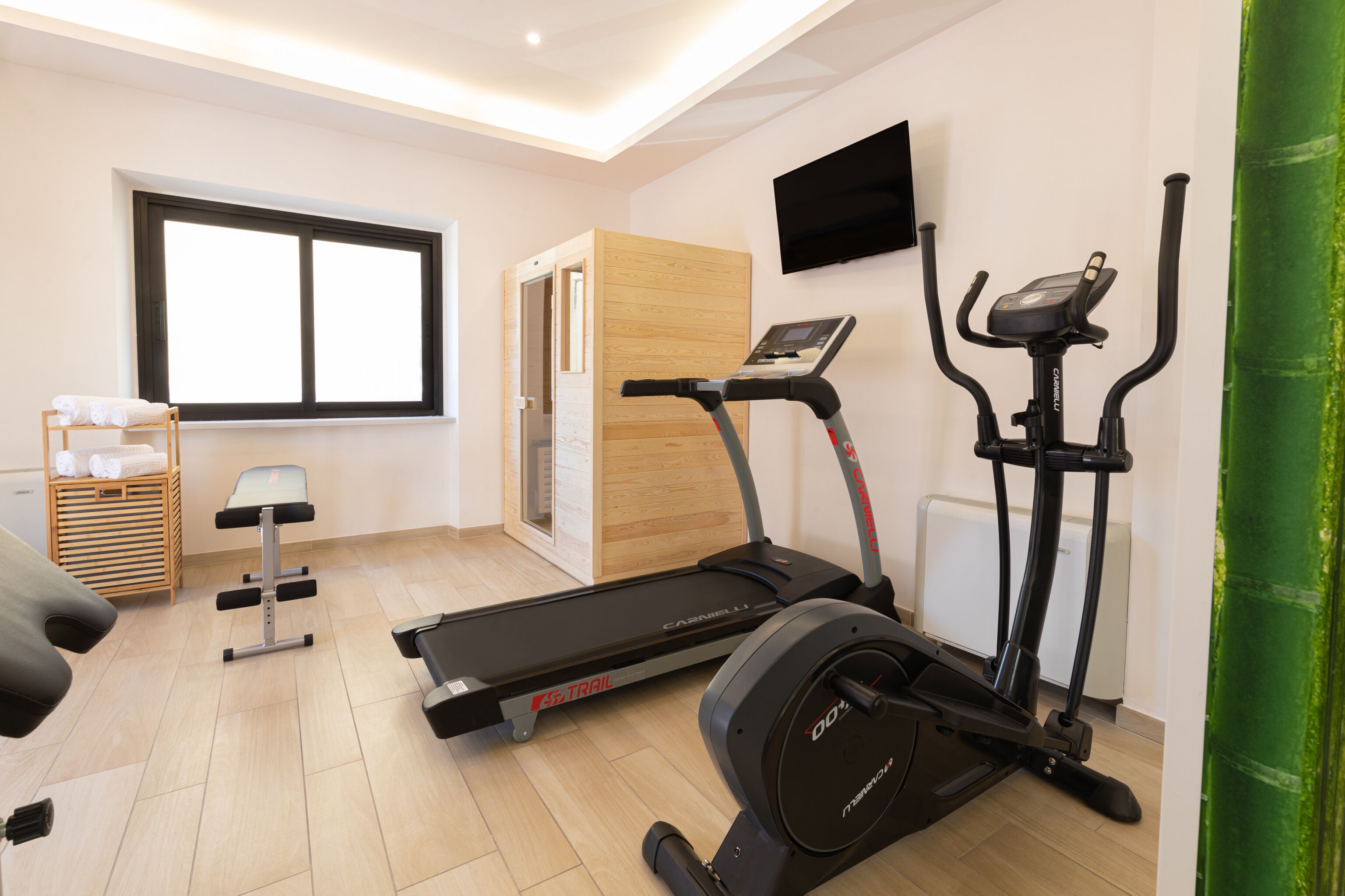 Une salle de sport moderne pour la maison, équipée d’un tapis de course, d’un vélo d’appartement et d’un banc de musculation.
